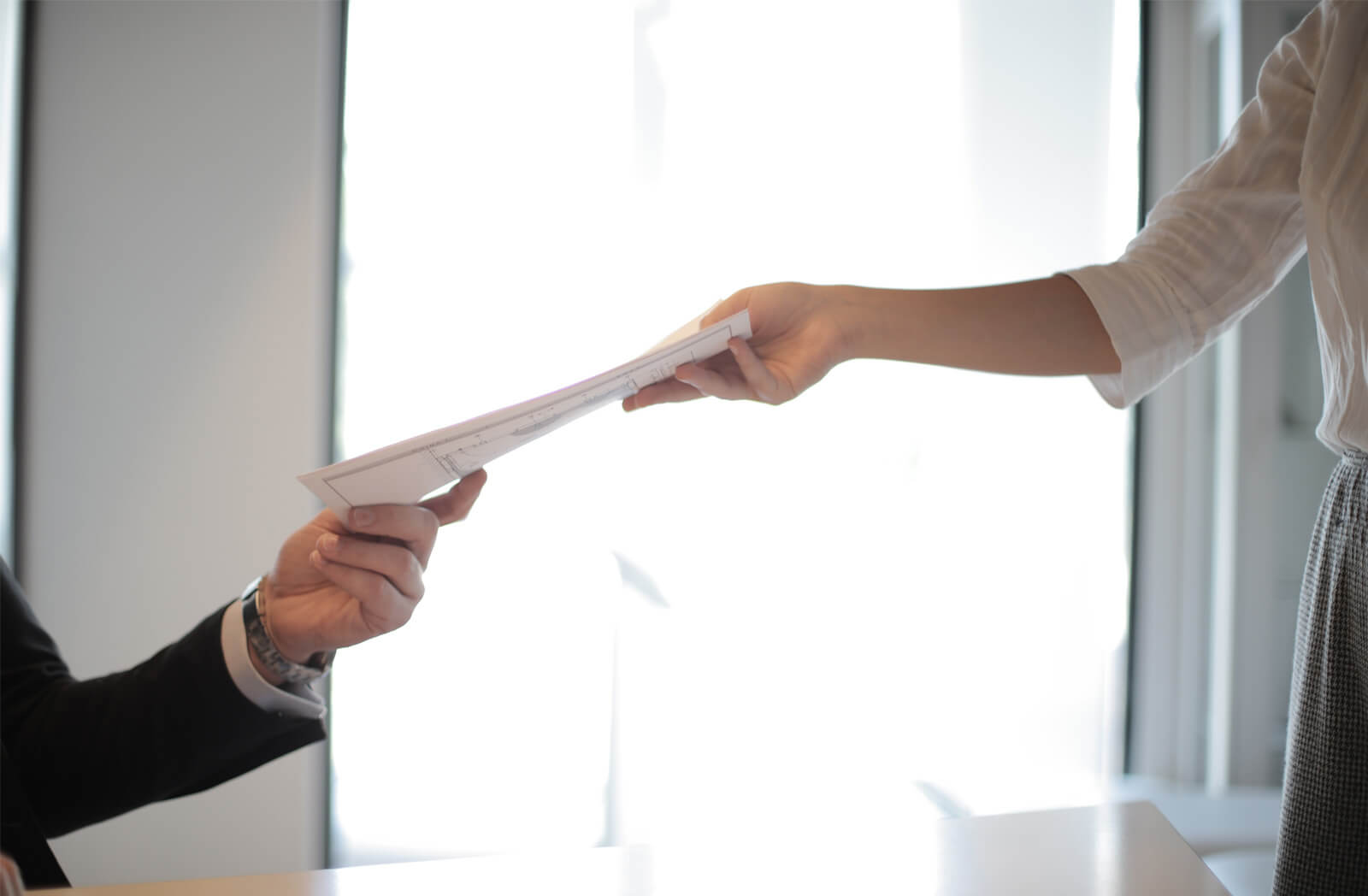 Two employees of a service contracting welding company passing document to each other