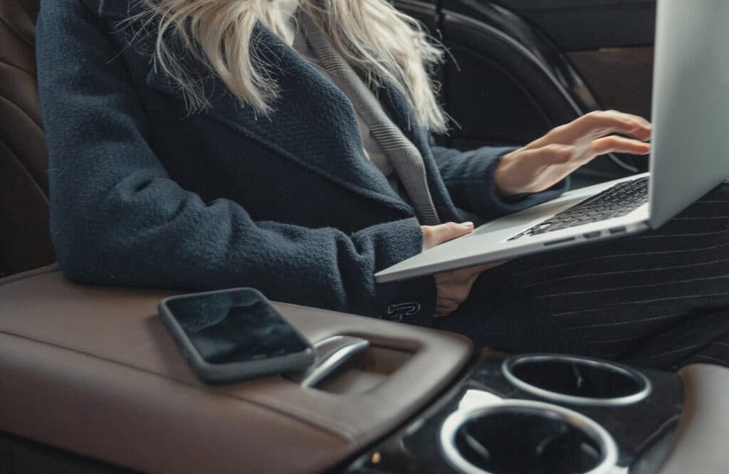 Blond woman holding laptop inside her car