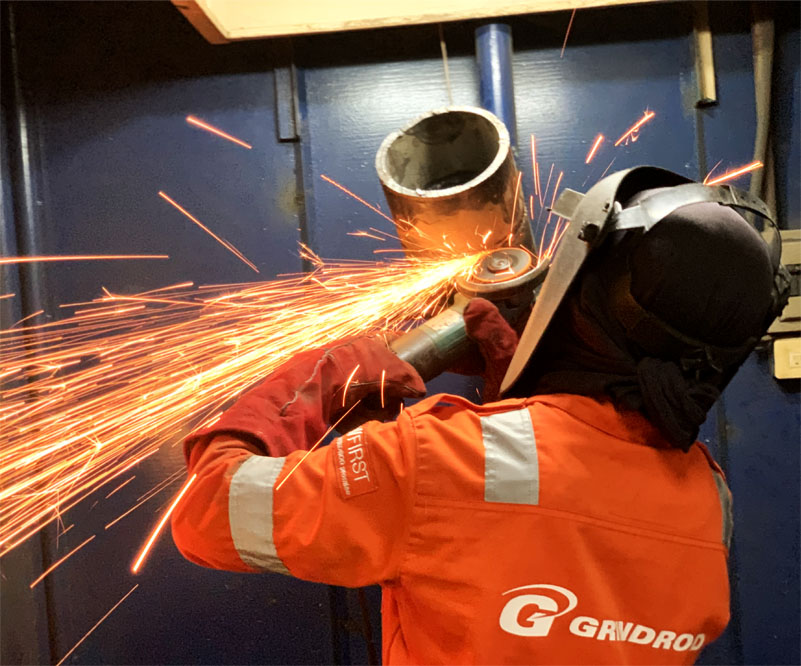 Welder in orange protective gear and welding Face shield used angle grinder
