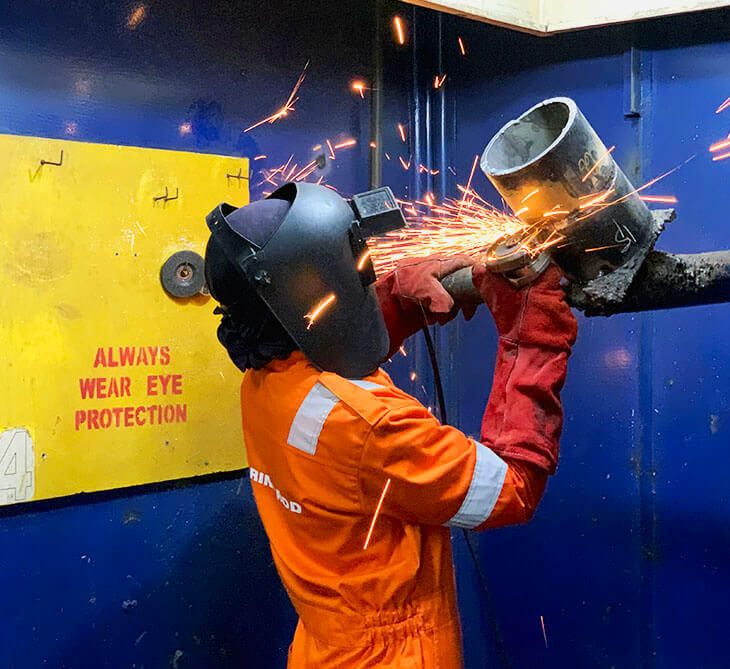 Welder in orange protective gear used angle grinder