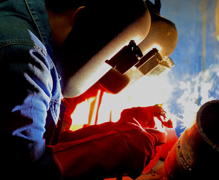 three welders in blue uniform, red welding gloves and Welding Mask