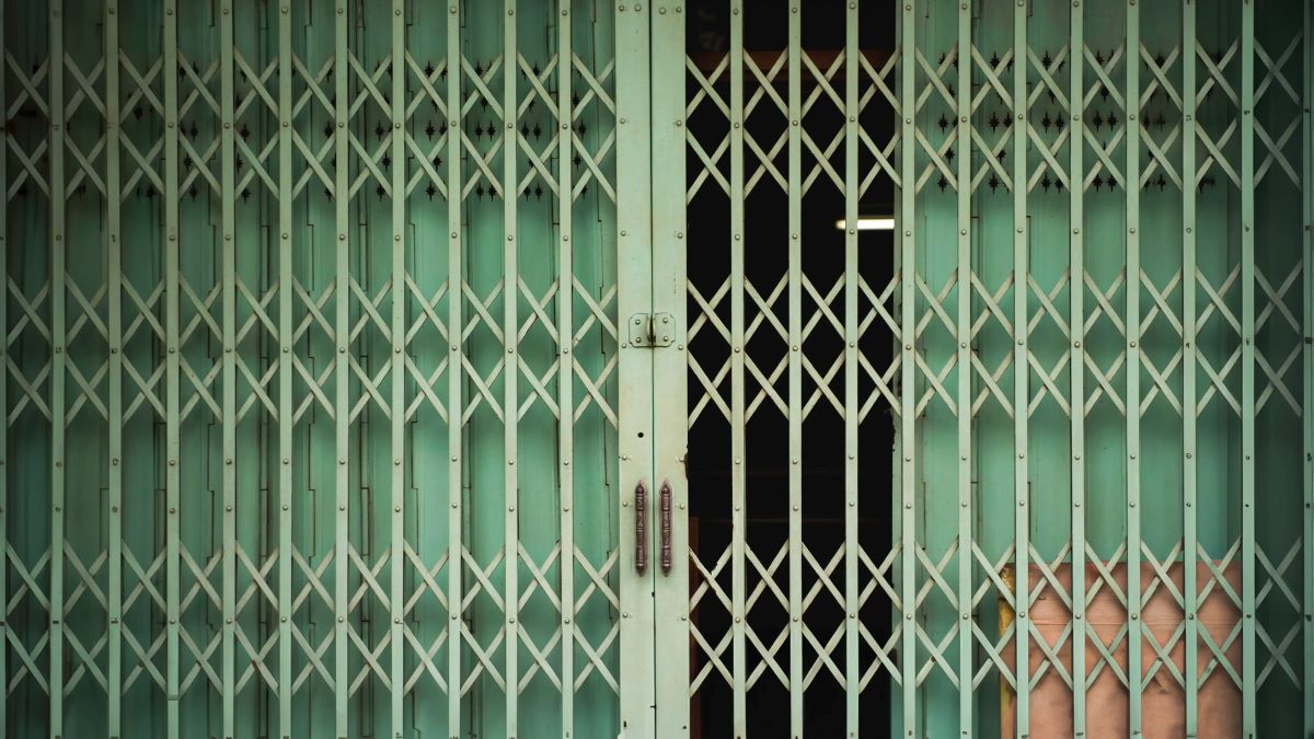 A green steel gate with slightly open door.